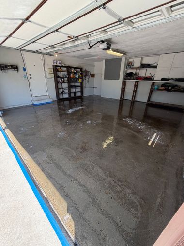 Empty concrete parking garage floor with wet, reflective surface and a support column