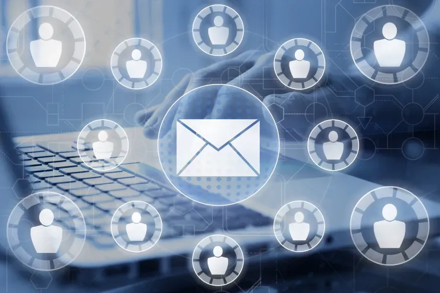 Person using laptop surrounded by glowing email and user icons, signifying network communication.