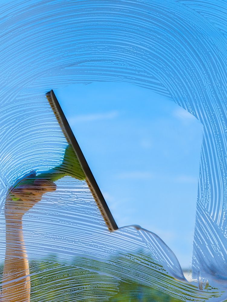 A person is cleaning glass with a high pressure washer — Pain in the Glass Window Cleaning in Airlie Beach, QLD