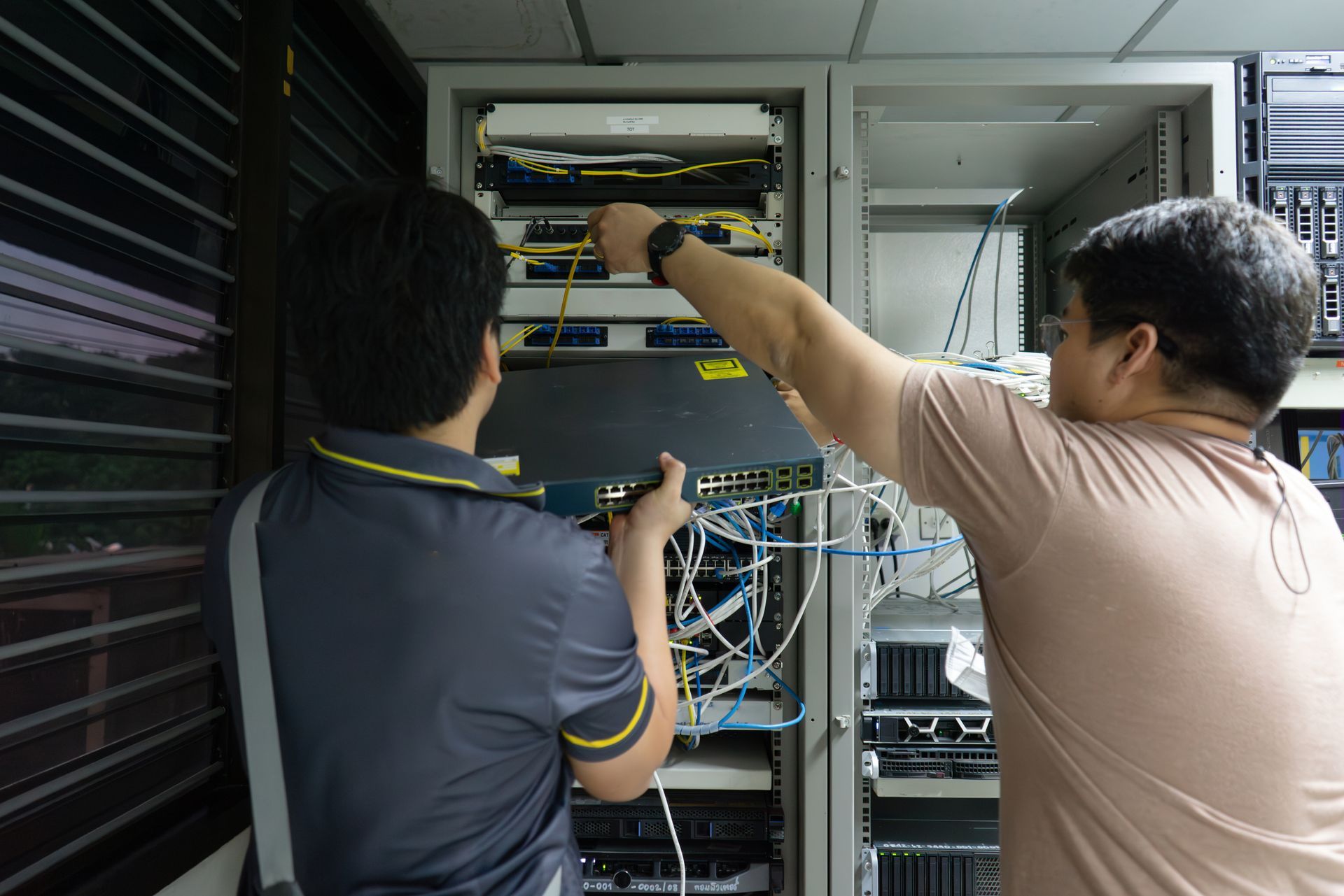 Two Technicians Wiring Network Equipment in A Server Rack Cabinet — Comms Cabling Central Coast In Kanwal, NSW