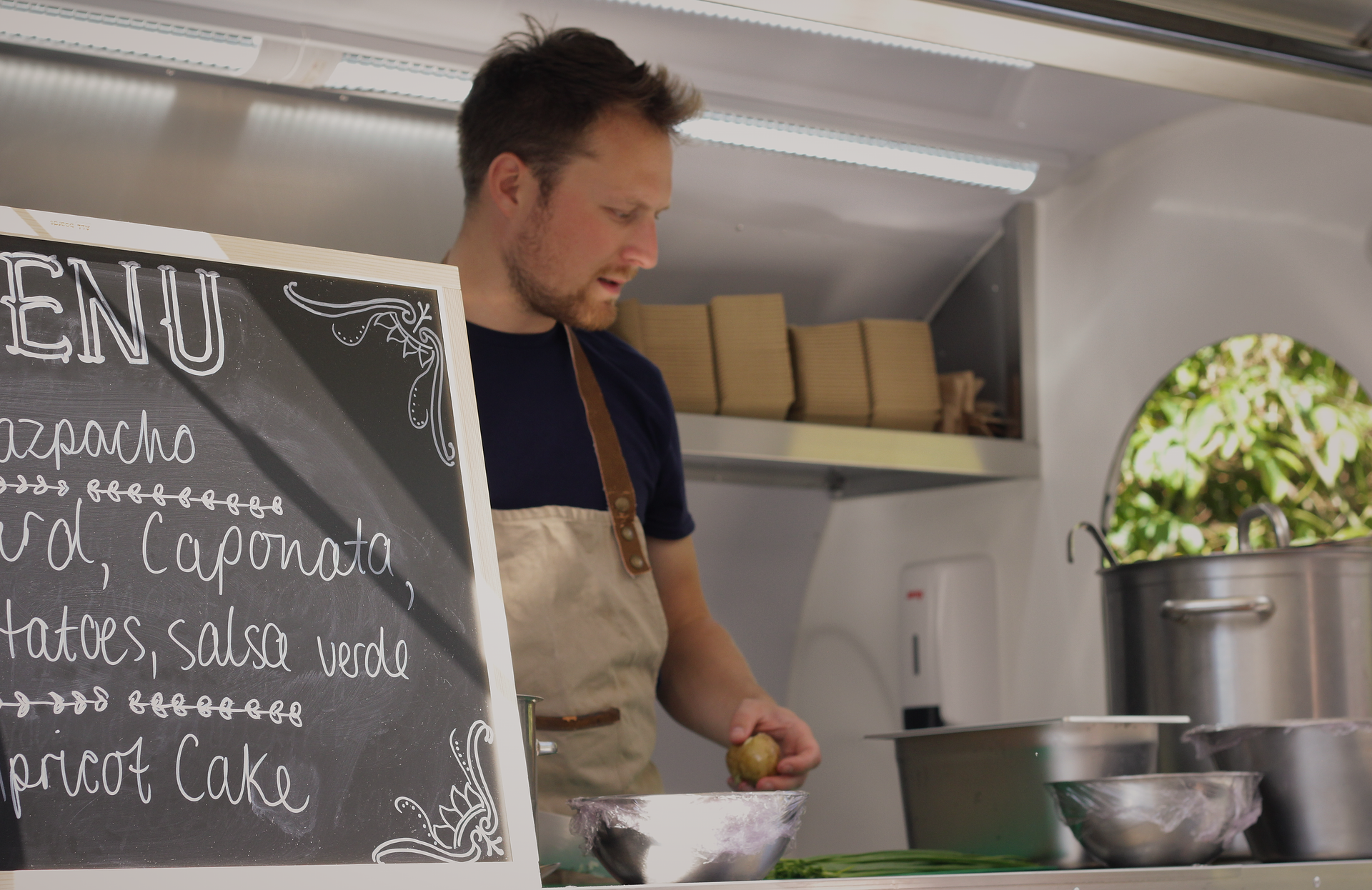 Chef preparing food in a kitchen beside a chalkboard menu