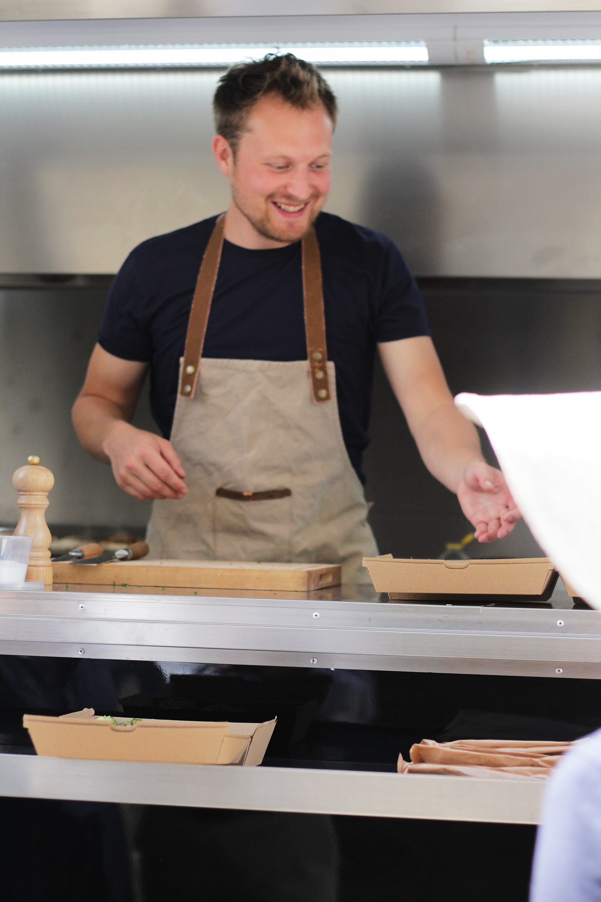 Chef smiling while preparing food behind a counter in a kitchen