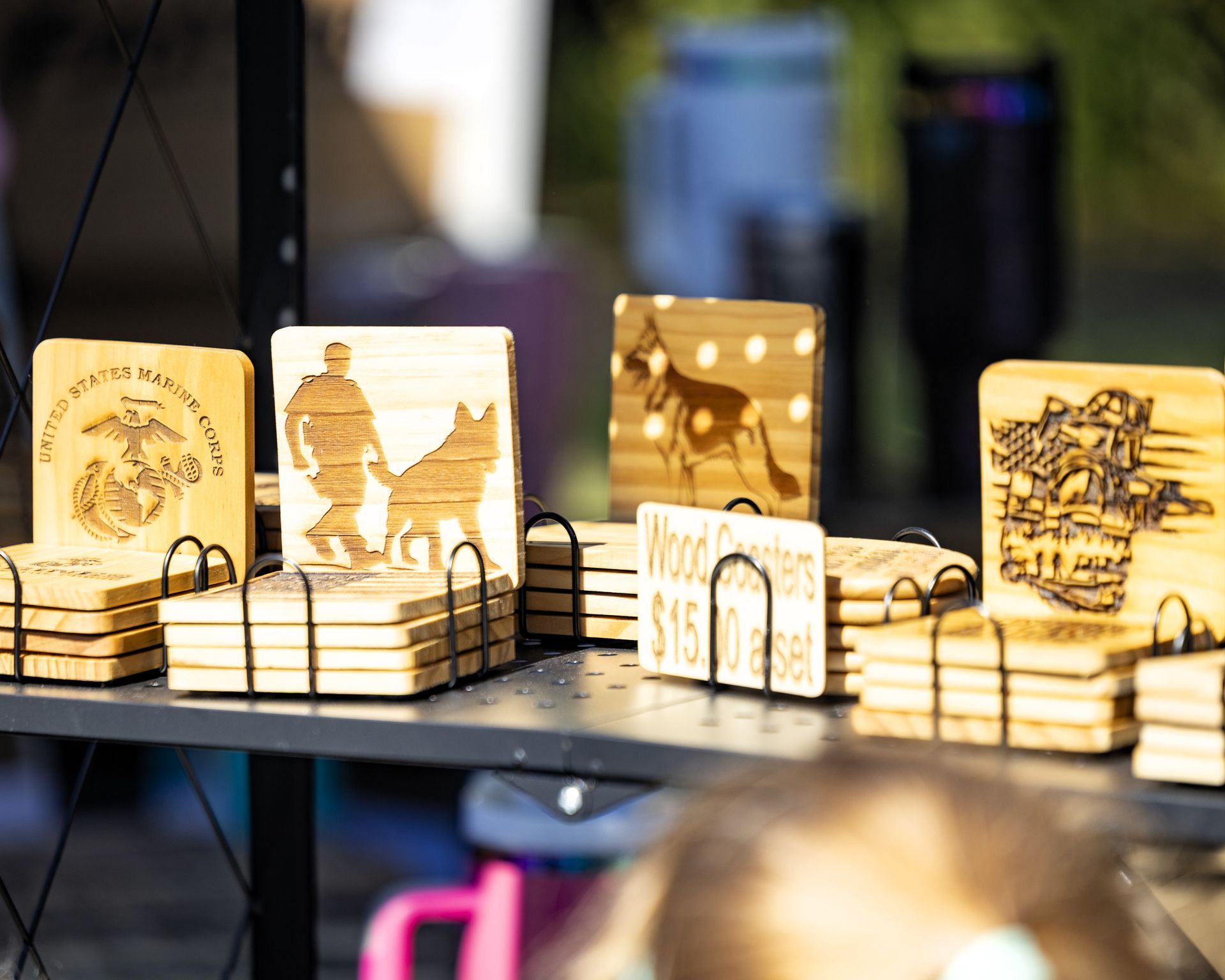 Wooden engraved coasters displayed on a black shelf with colorful blurred background lights
