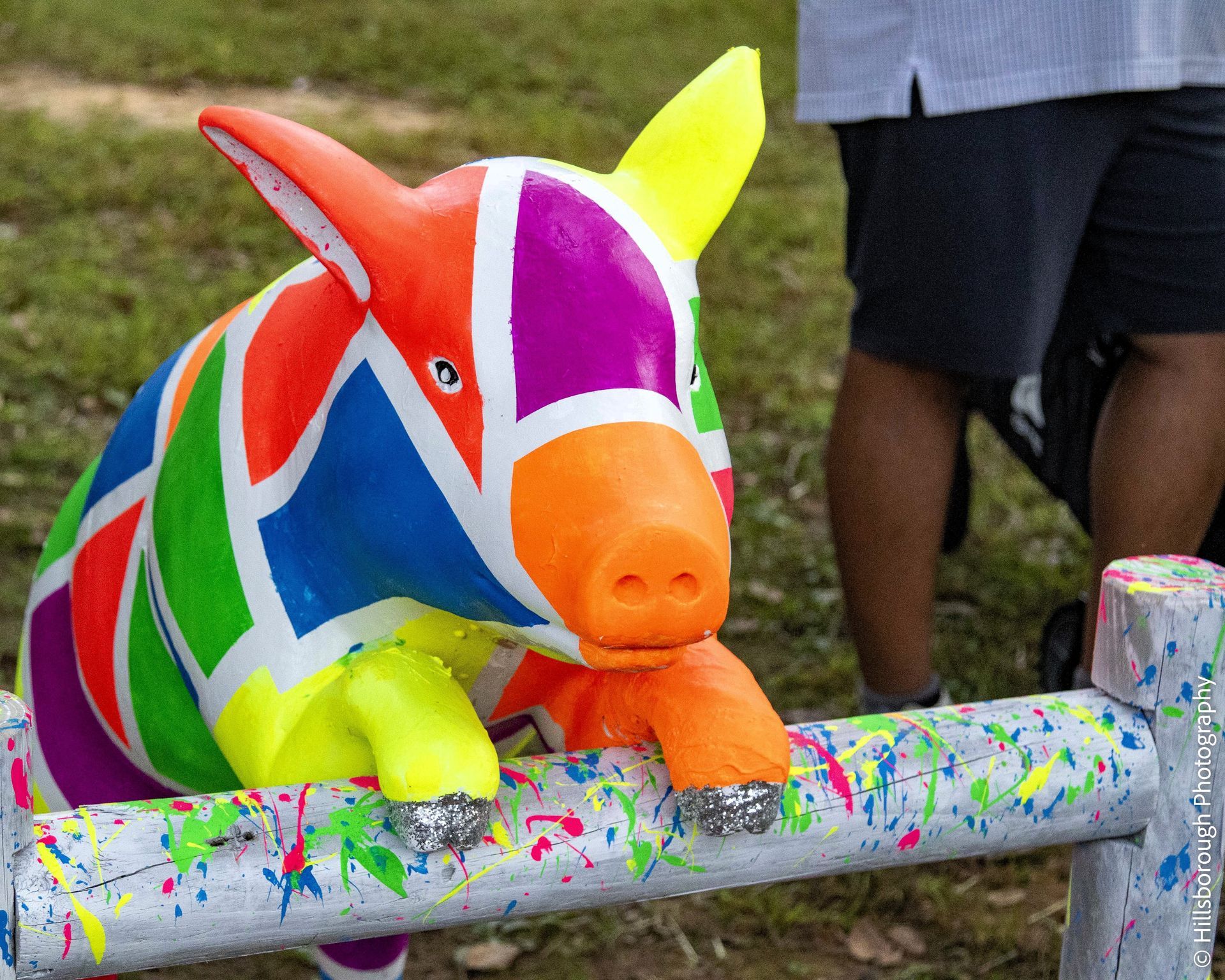 Colorful painted pig sculpture on a splattered bench outdoors