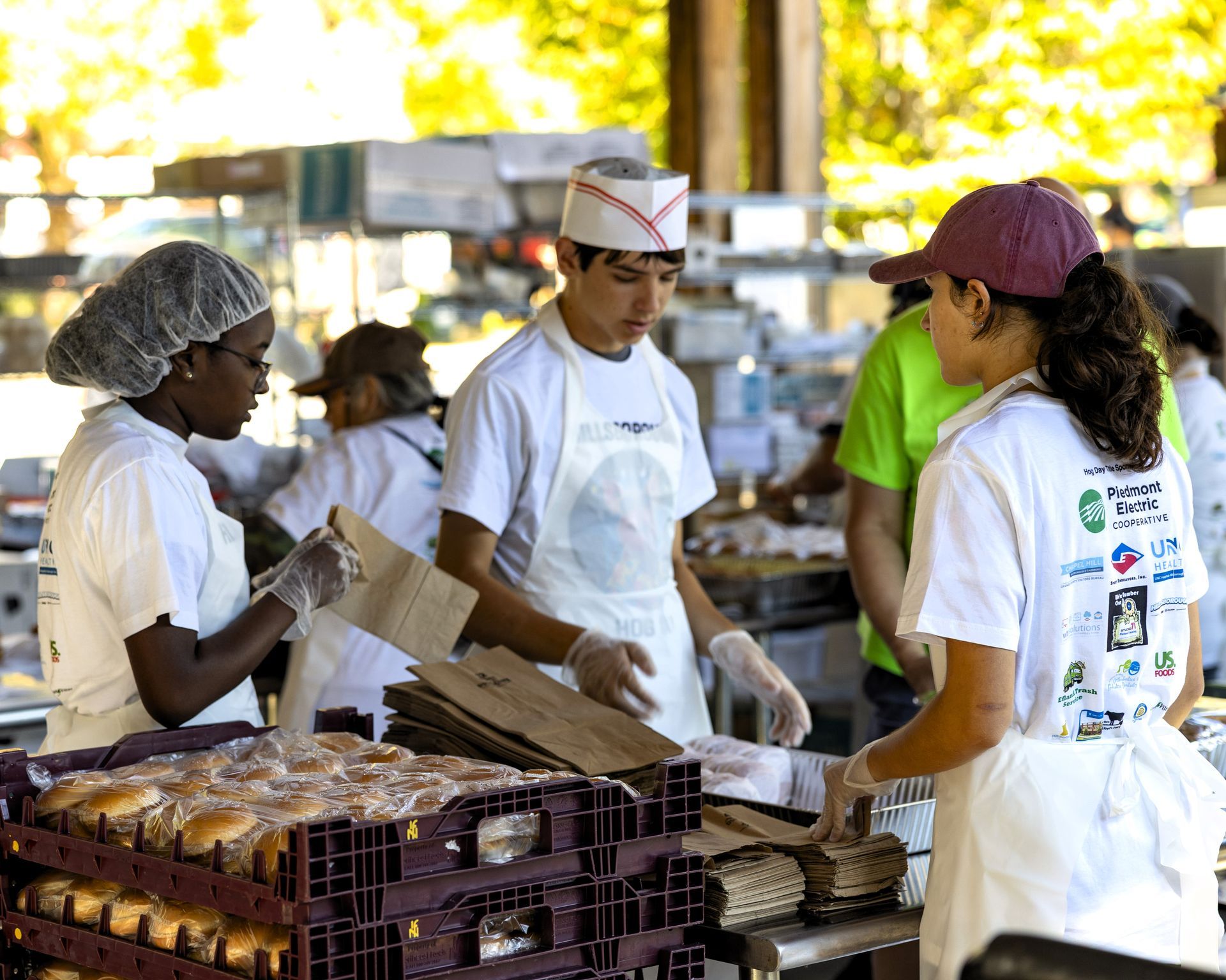 Workers packaging baked goods at a table in a bright kitchen or bakery setting