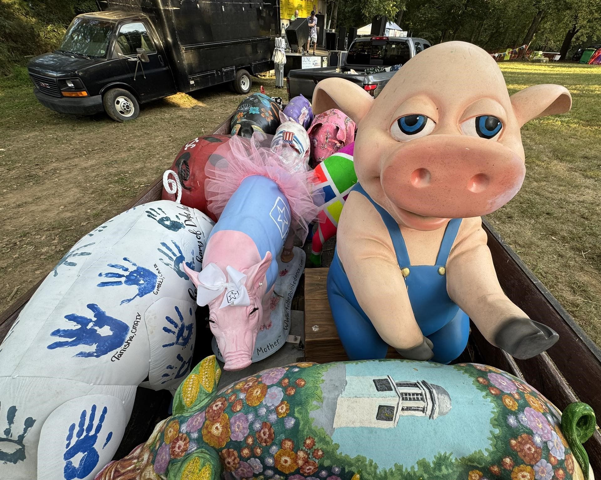 Inflatable pig and decorative yard sculptures displayed outdoors on a trailer or cart