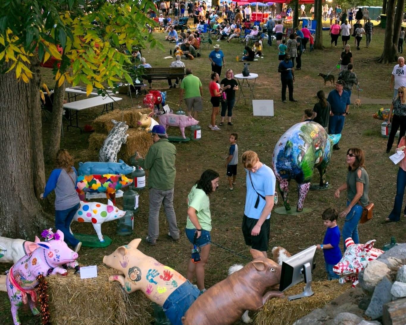 Crowd at an outdoor park festival with colorful art installations and people walking among trees