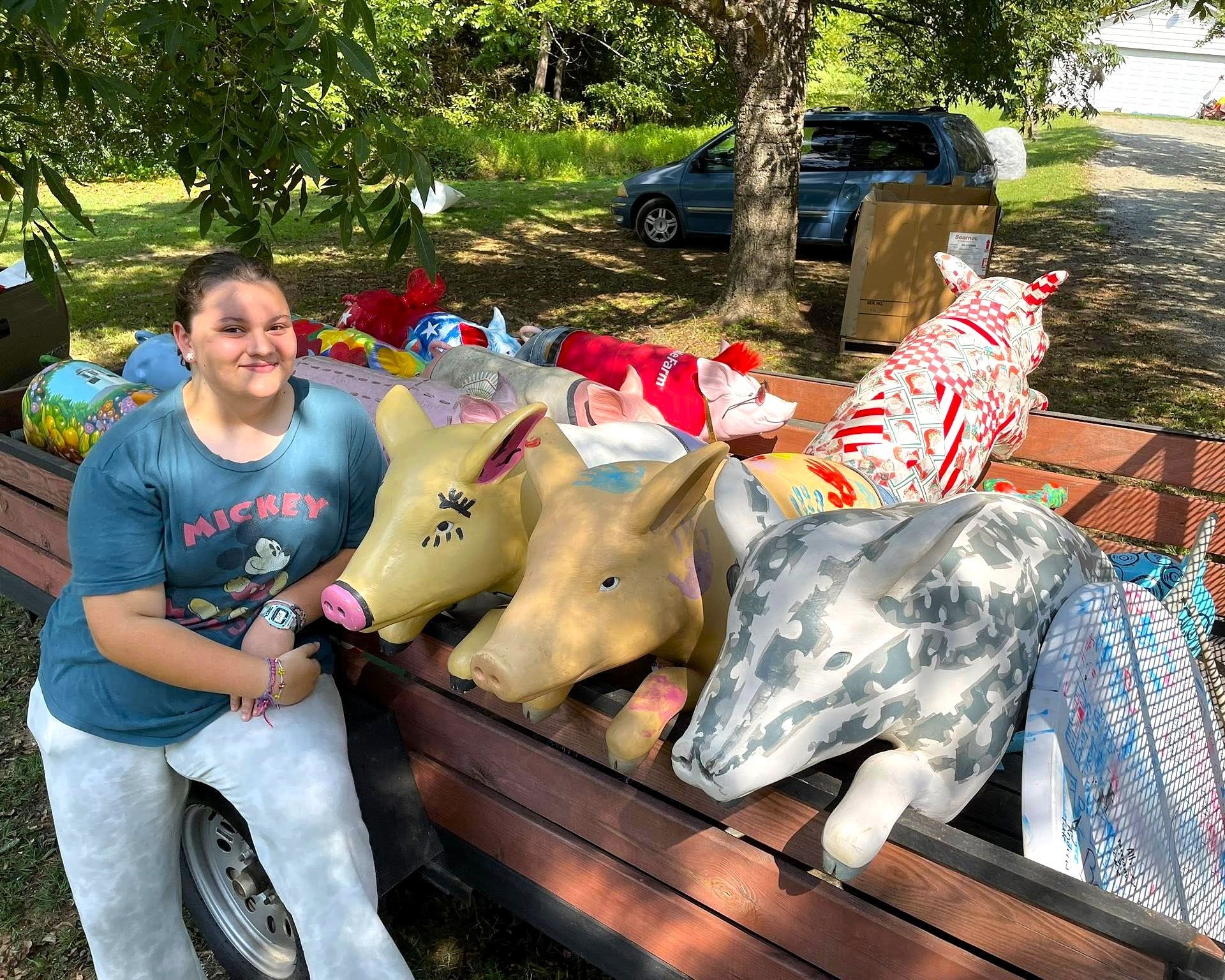 Person sitting on a bench with large stuffed animals in a sunny park.