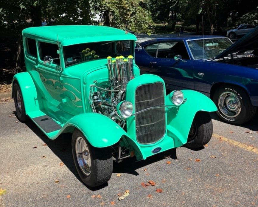 Bright green vintage hot rod parked outdoors with exposed engine and chrome details