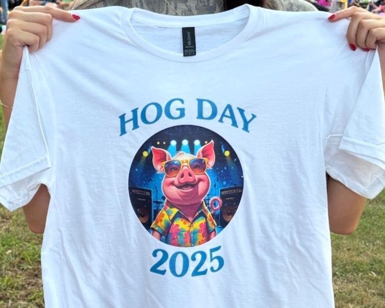 White “HOG DAY 2025” T-shirt with a colorful pig graphic, held up outdoors