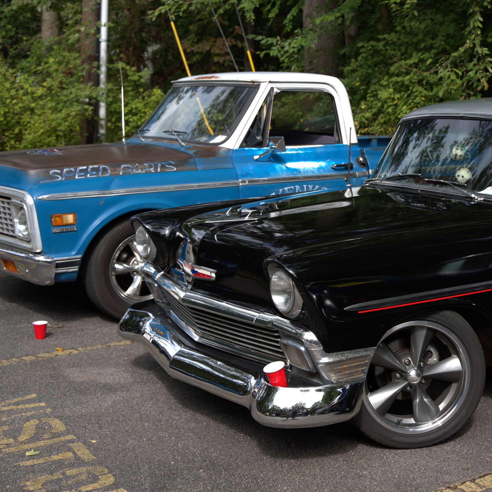 Blue and black classic pickup trucks parked side by side outdoors at a car show