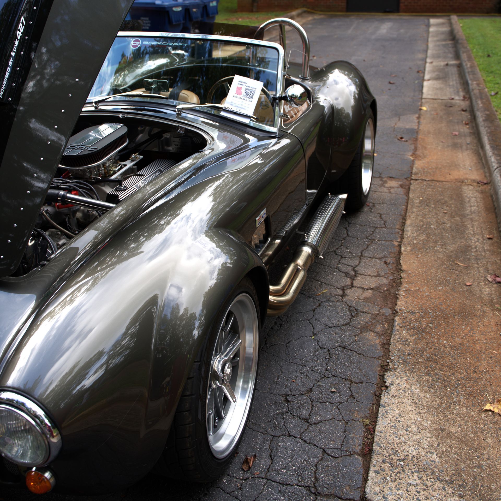 Silver classic convertible sports car parked on a street, viewed from the front-left side.
