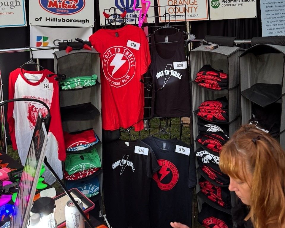 Merchandise stall with red and black graphic T-shirts hanging on display racks