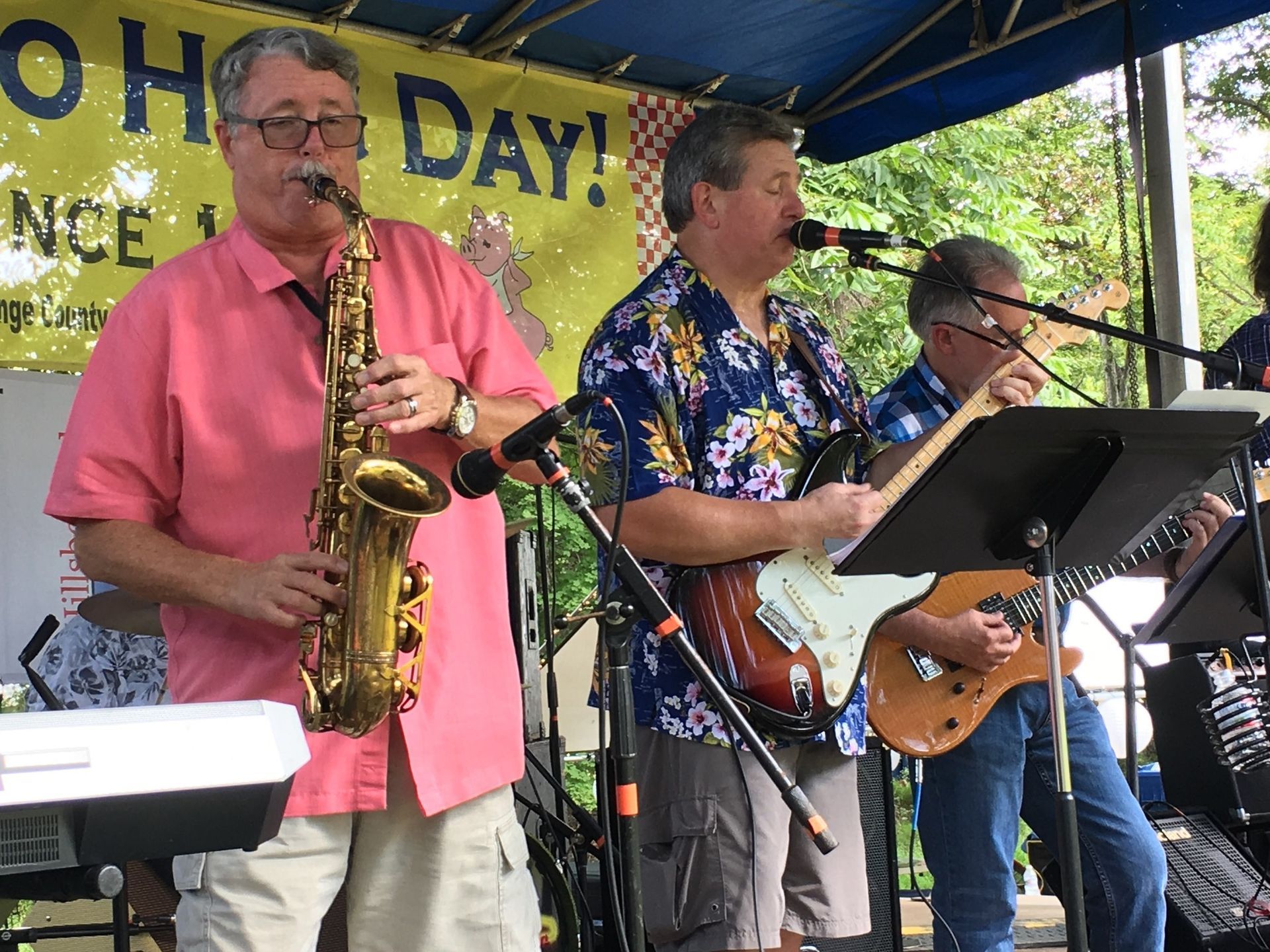 Trio of of men playing saxophone and two guitars as band