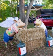 Two painted pig sculptures on a hay bale
