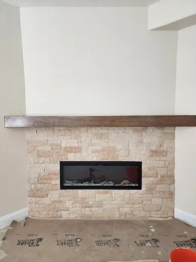 Fireplace with stone surround, dark mantel, and electric insert on a neutral wall.