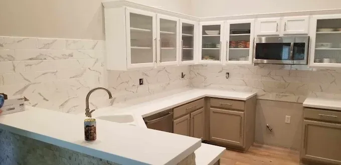 Newly renovated kitchen with white countertops, light brown cabinets, and white marble backsplash.
