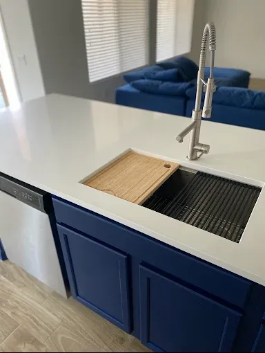 Kitchen island with blue cabinets, white countertop, and stainless steel sink.