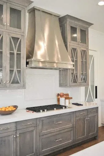 Kitchen with gray cabinets, a stainless steel range hood, white countertops, and a gas cooktop.