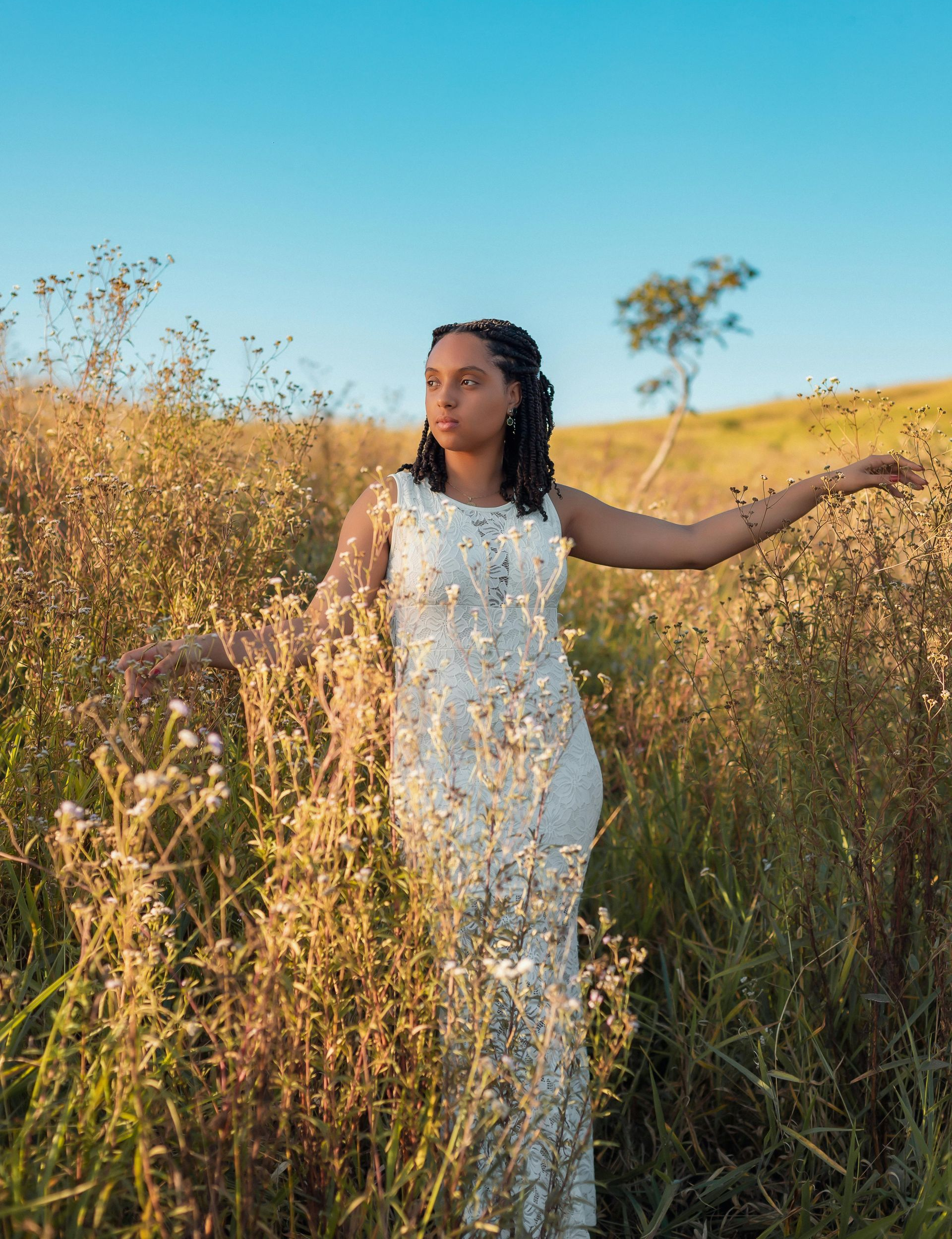 woman standing in a field, touching wheat and flowers