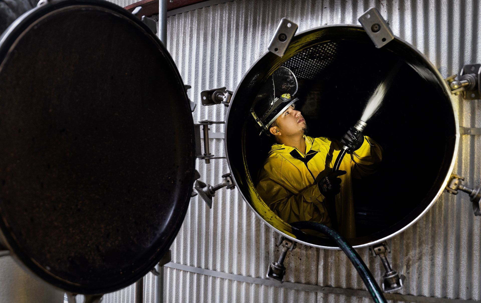 Industrial technician managing high-pressure cleaning equipment during ethanol plant maintenance operations, demonstrating specialized safety protocols and industrial cleaning processes.
