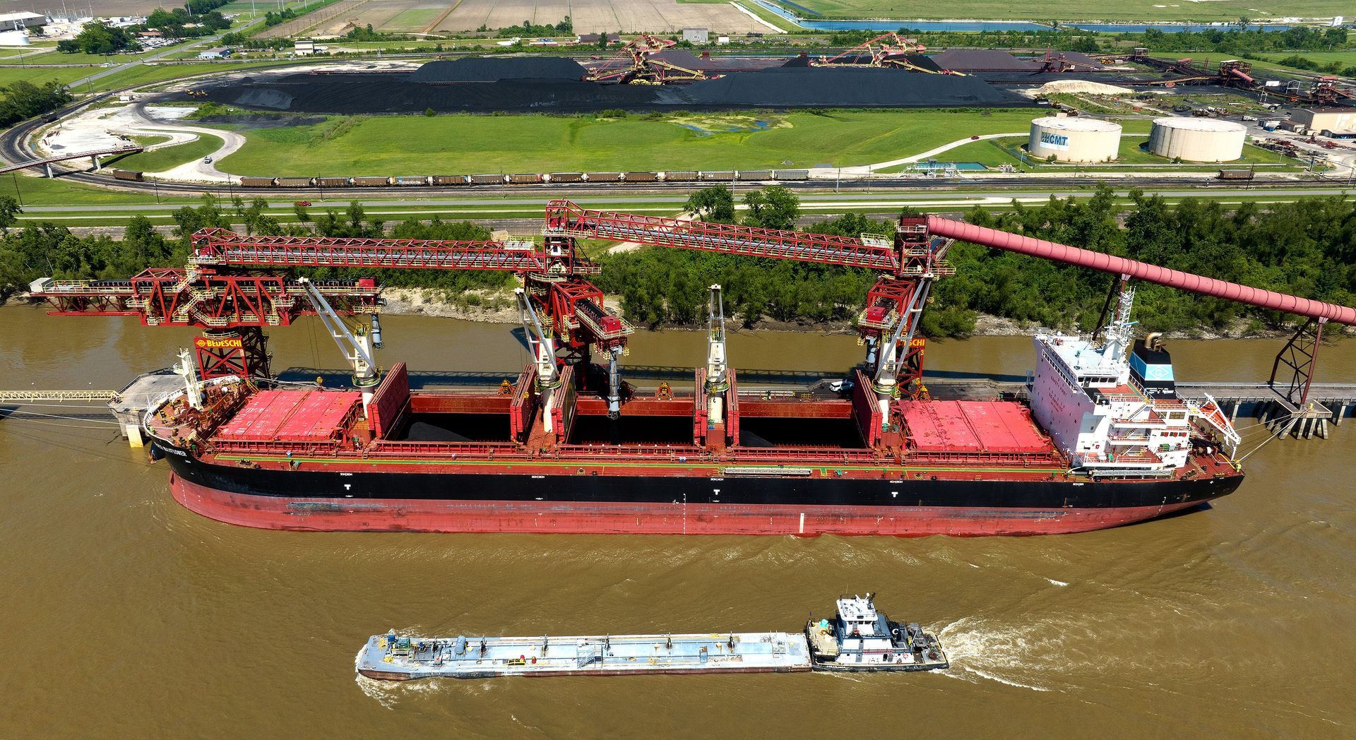 Drone photograph of a cargo ship receiving product at an industrial manufacturing facility. Image was taken by an FAA certified drone photographer who specializes in photographing heavy industrial manufacturing and operations. 