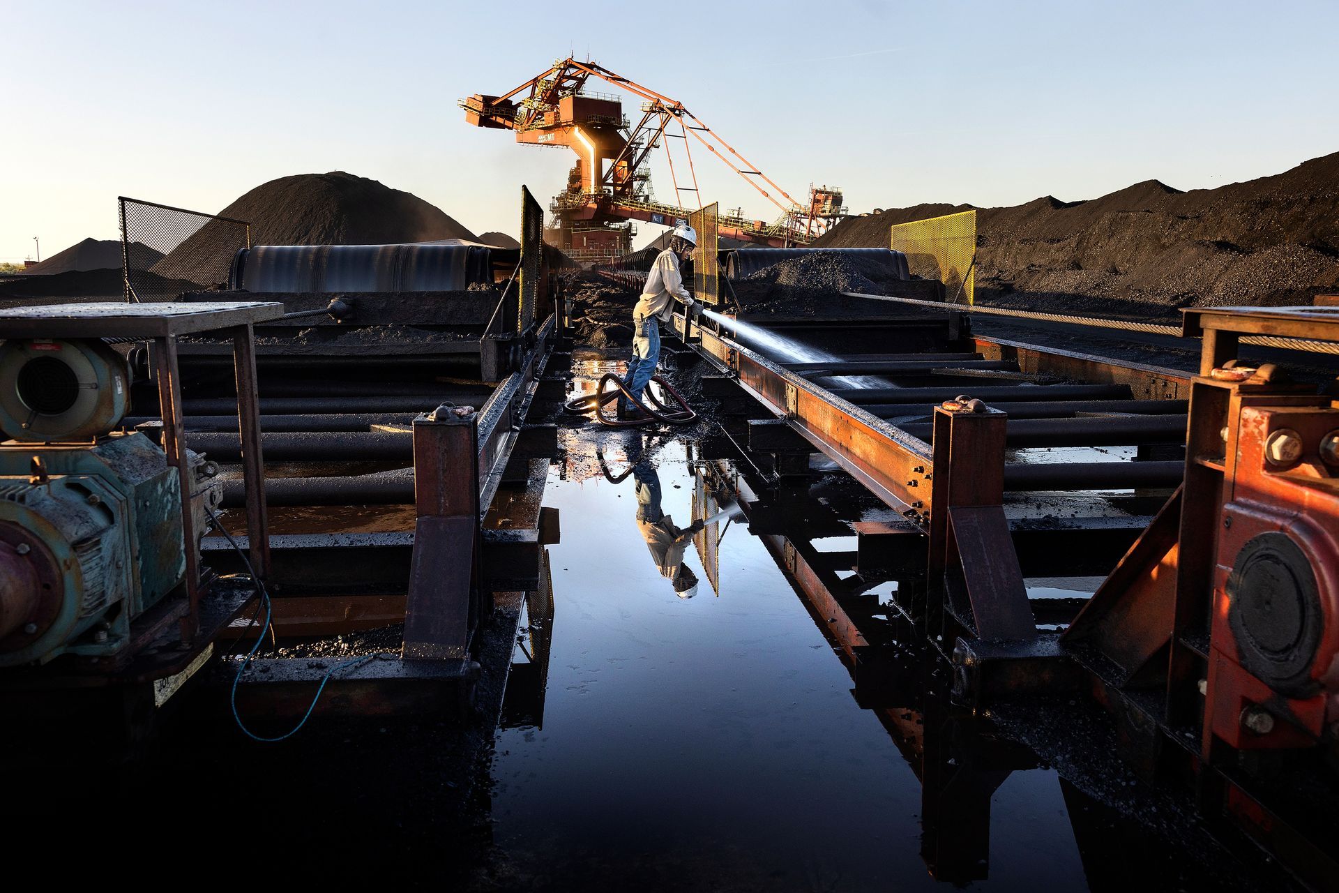 A worker hoses clean equipment at an industrial facility.
