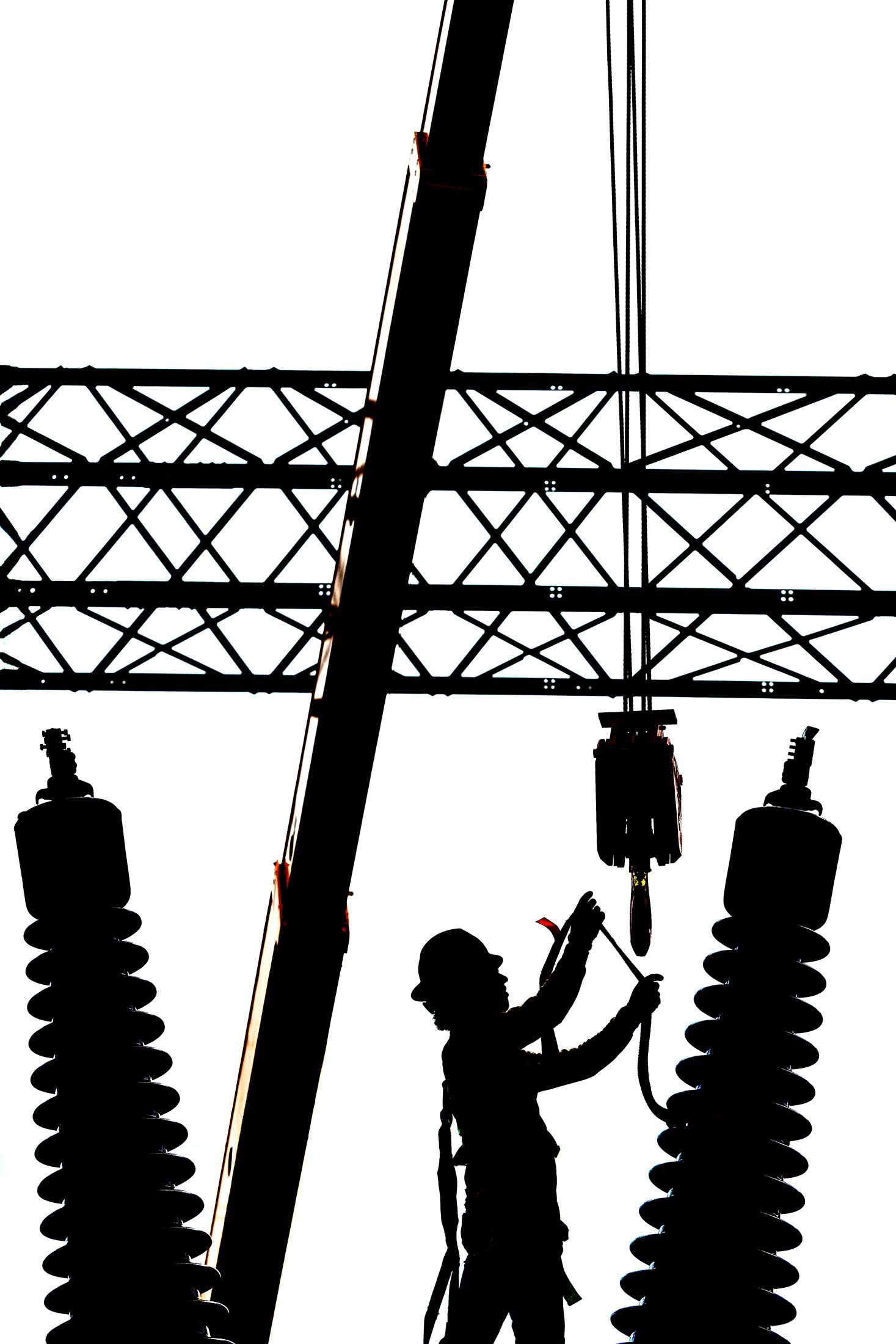 Industrial technician performing precision assembly of high-voltage equipment at electrical substation, demonstrating specialized safety protocols and technical expertise.