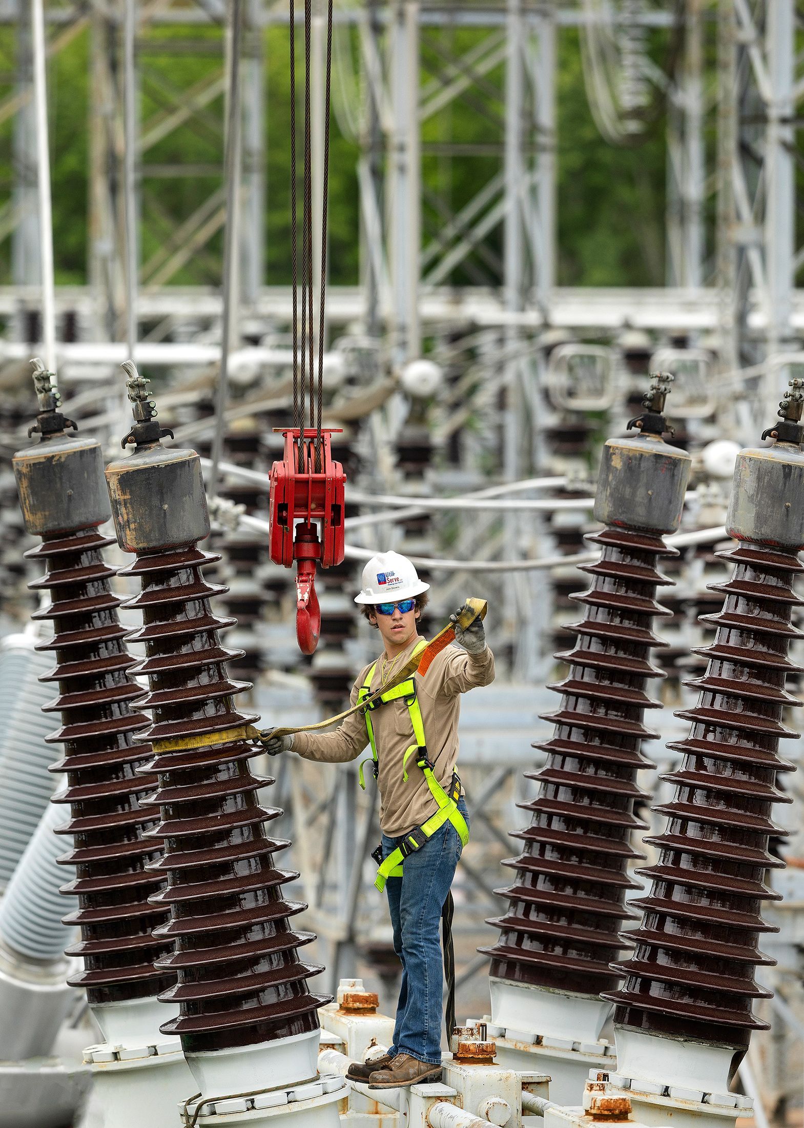 Utility infrastructure specialist conducting critical equipment installation at power distribution substation, showcasing industrial electrical assembly processes.