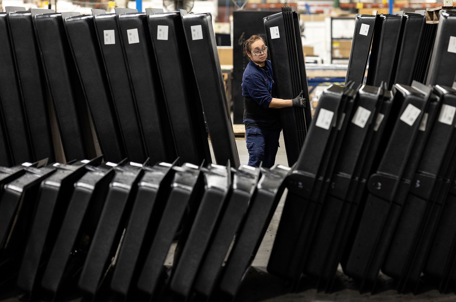 A worker in a plastics manufacturing facility lifts large bins used for liquid storage.
