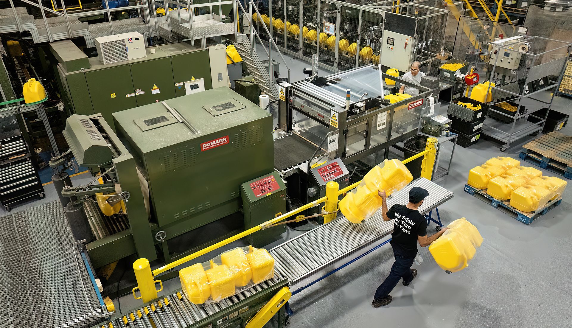 Worker in a plastic manufacturing facility carries plastic bins off the assembly line. Photographer used drone inside facility to show size and scale of manufacturing operations.