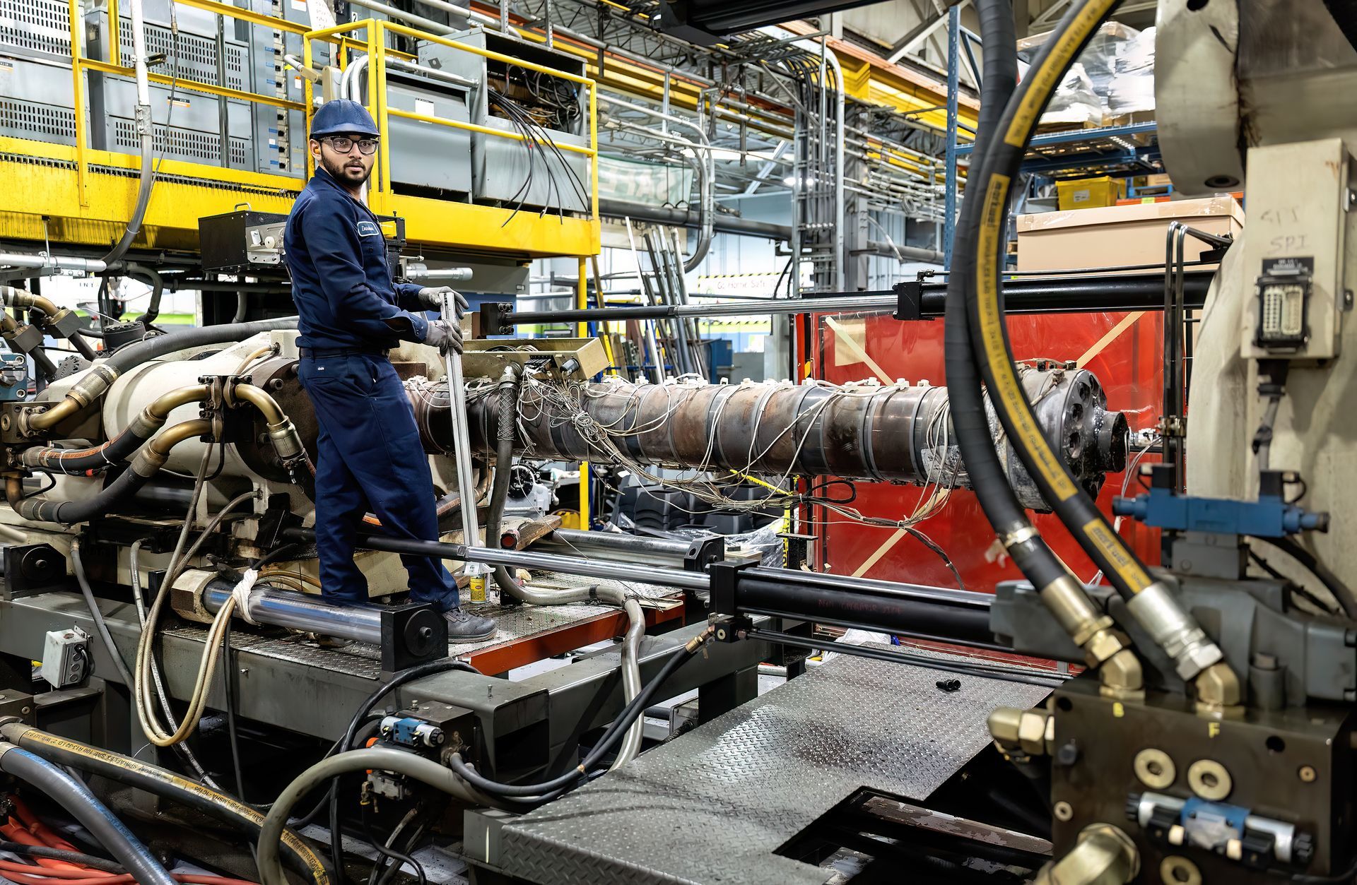 A worker uses a large wrench to adjust a piece of equipment on a manufacturing line in an industrial facility.