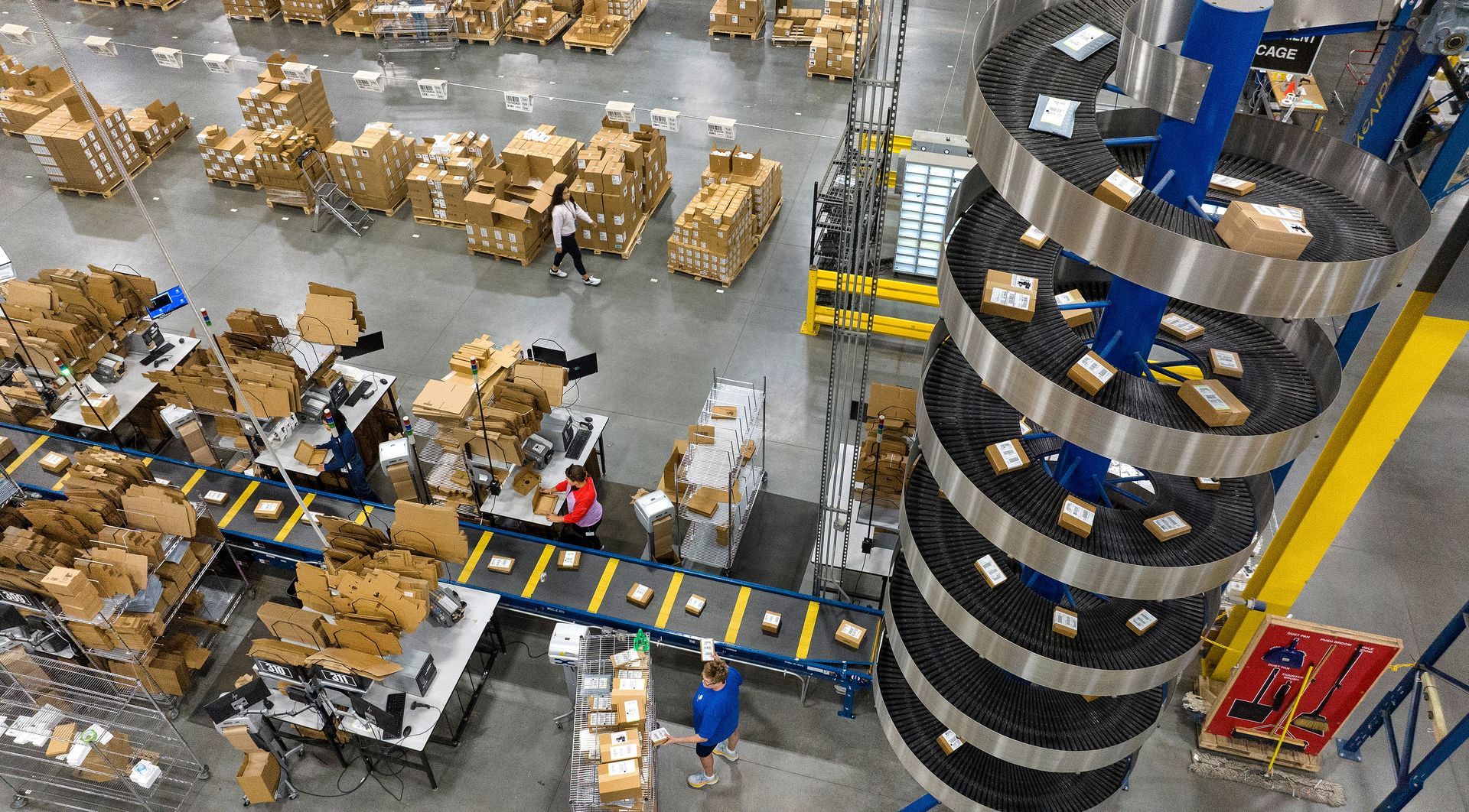 Overhead view of workers packaging products into boxes on an assembly line. Photographer used a drone to create an overhead photo that shows the size and scale of the logistics facility.