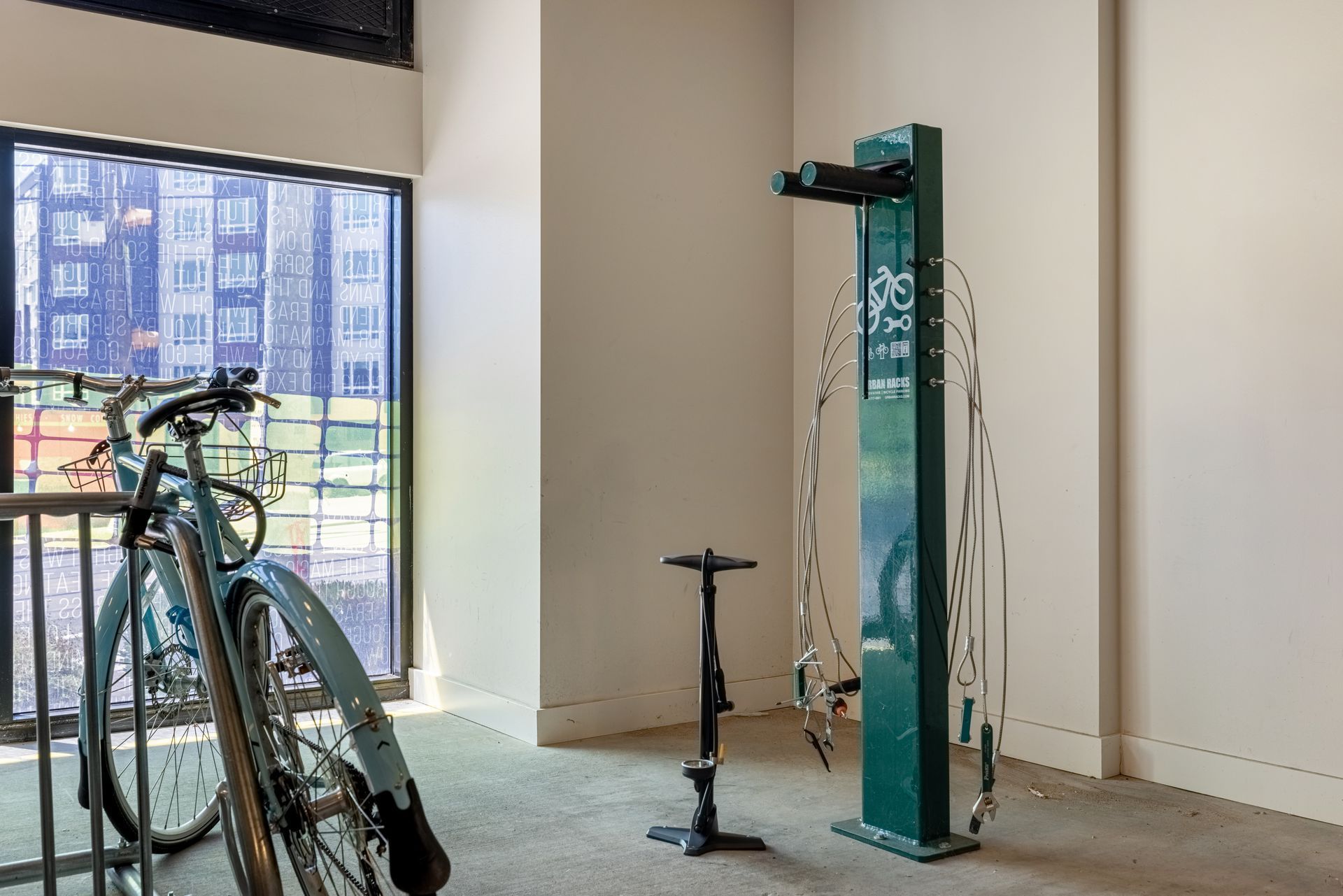 Indoor bike repair stand beside a bicycle near a large window, with city buildings outside at Anthem on 12th, offering luxury apartments near Downtown Seattle, WA.