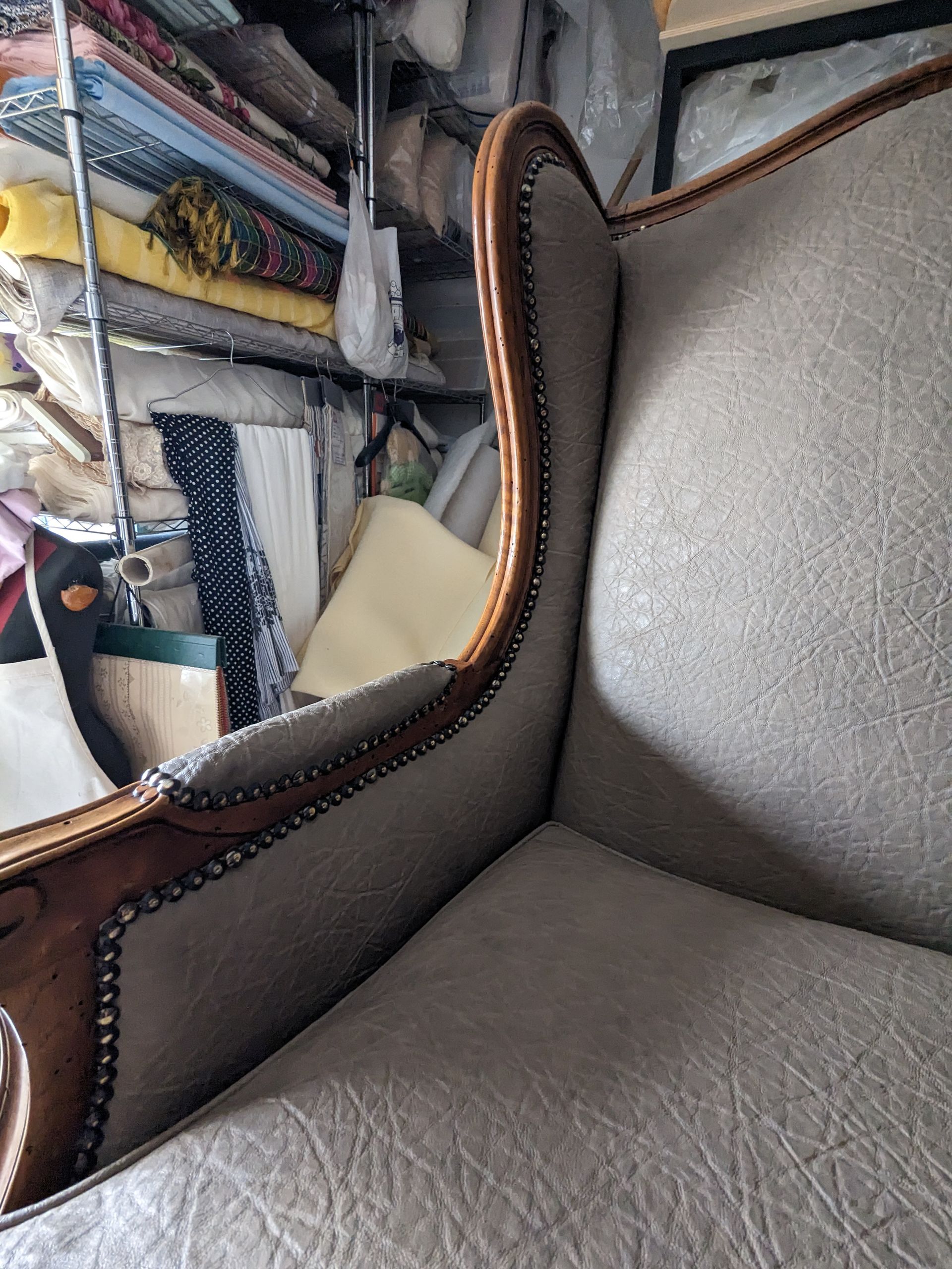 Primo piano di una poltrona in pelle grigia con finiture marroni in un camerino di prova di un negozio di abbigliamento.