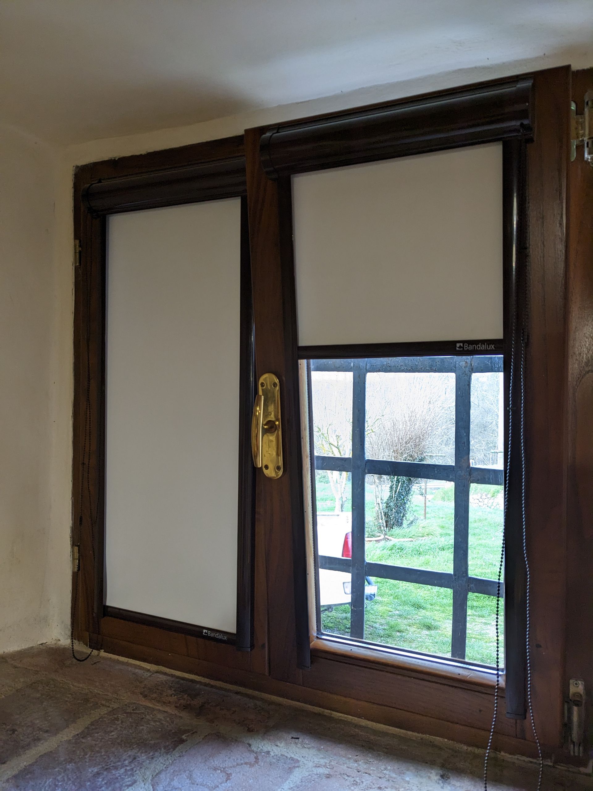 Finestra con telaio in legno, pannelli satinati e vetro inferiore trasparente, affacciata su un cortile.