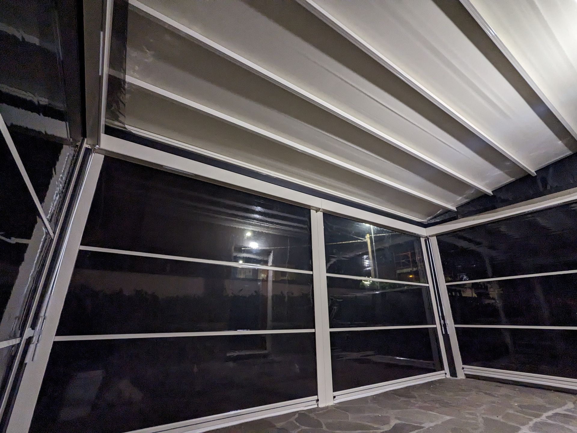 Veranda vuota con zanzariere, travi bianche e pannelli delle finestre scuri, di notte.