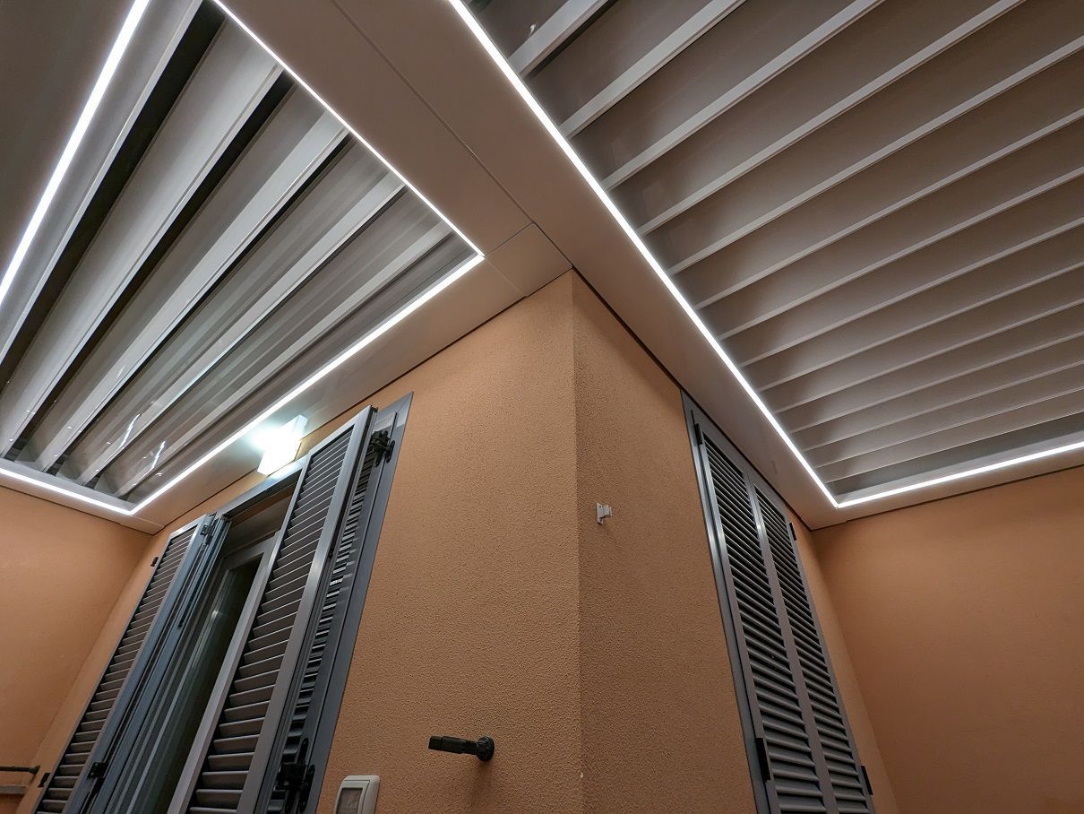Angolo interno con pareti beige e bocchette di ventilazione a lamelle sul soffitto, visto dal basso verso l'alto, vicino al pavimento.
