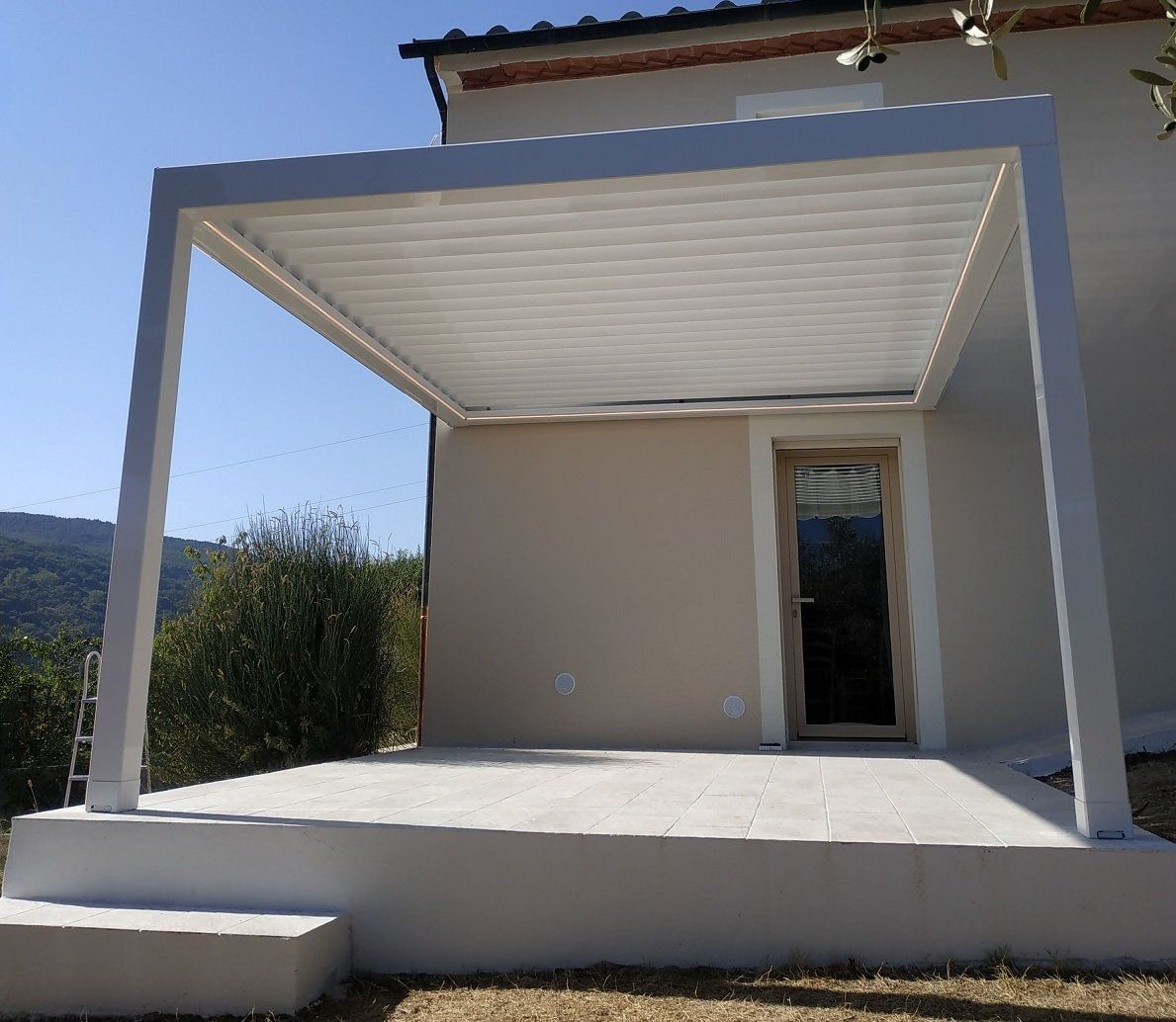Piccolo patio moderno con tetto bianco, parete beige e porta a vetri su una piattaforma rialzata in cemento.