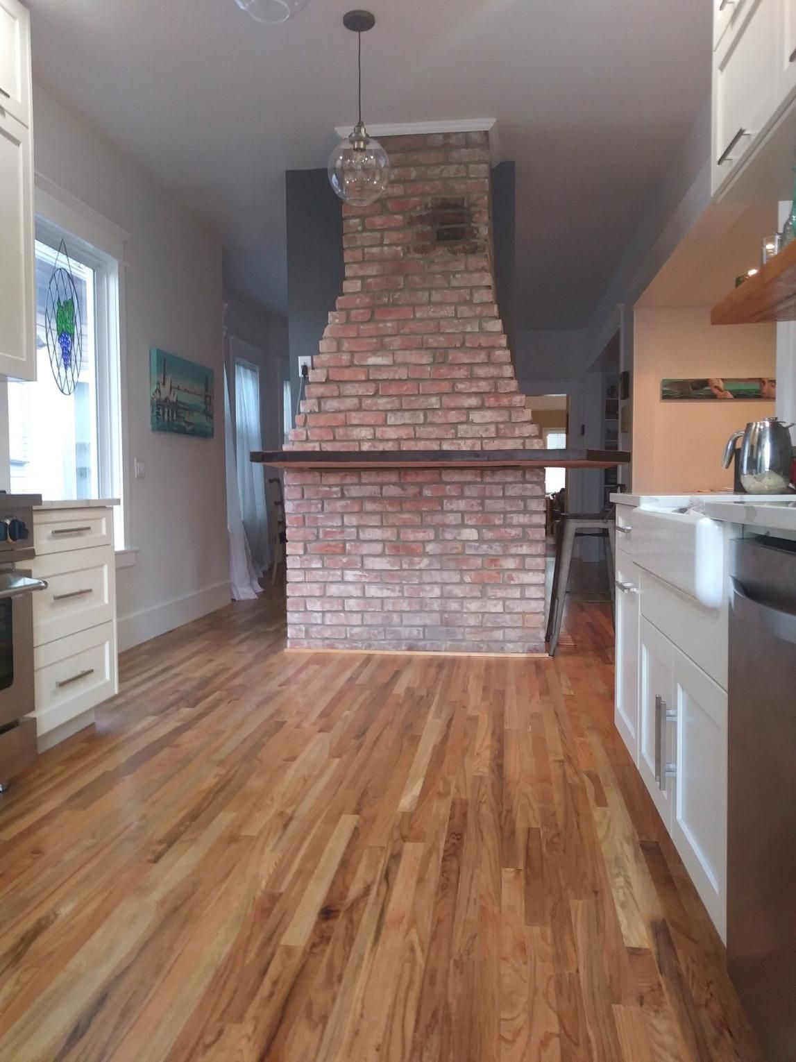 Narrow kitchen with hardwood floor and a central brick chimney or fireplace in the middle of the room