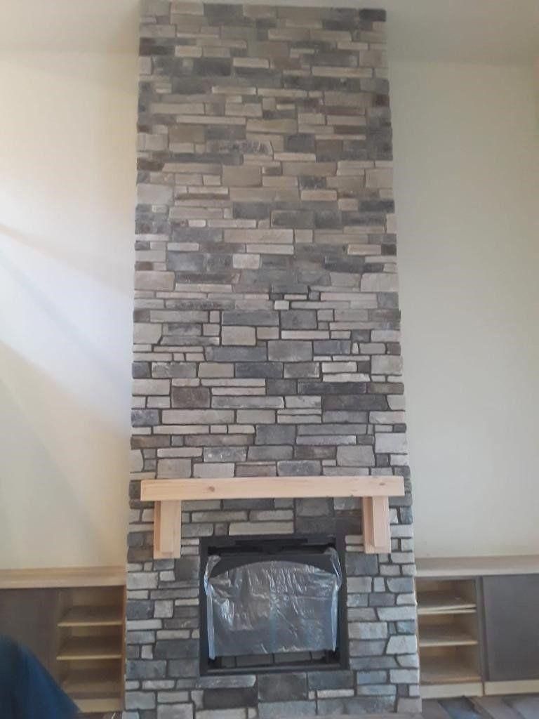 Stone fireplace with a tall tiled chimney and wooden mantel in a sparsely furnished room