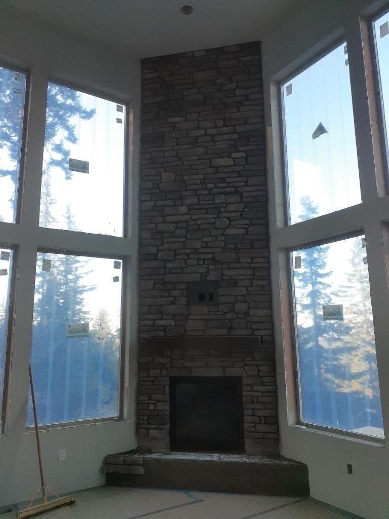 Stone fireplace with a high windowed wall and blue sky visible outside