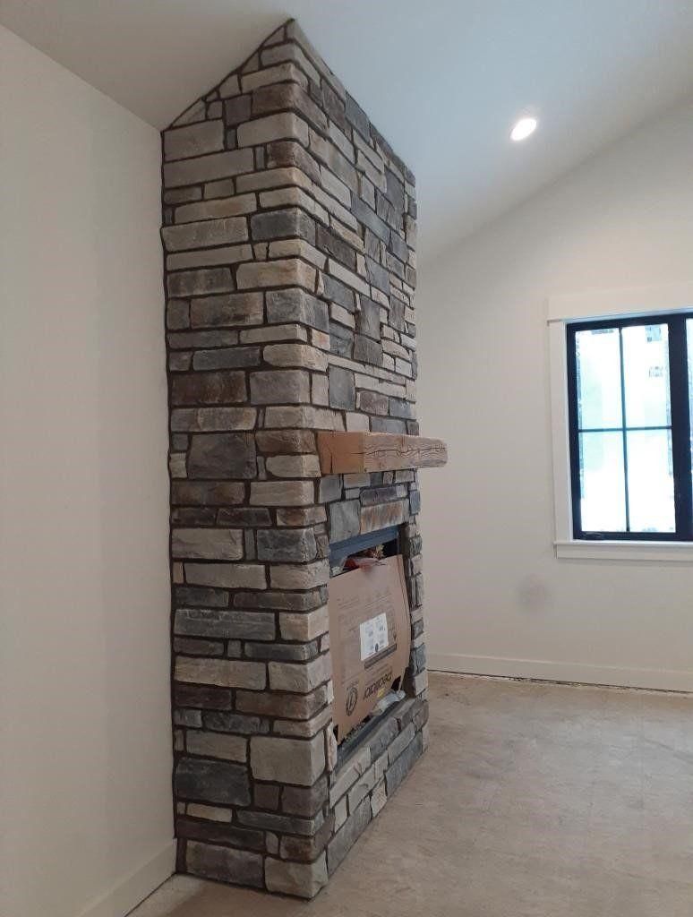 Stone-clad fireplace column in an empty room with white walls and a window