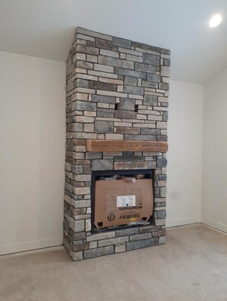 Stone fireplace surround in a carpeted room with a recessed light overhead