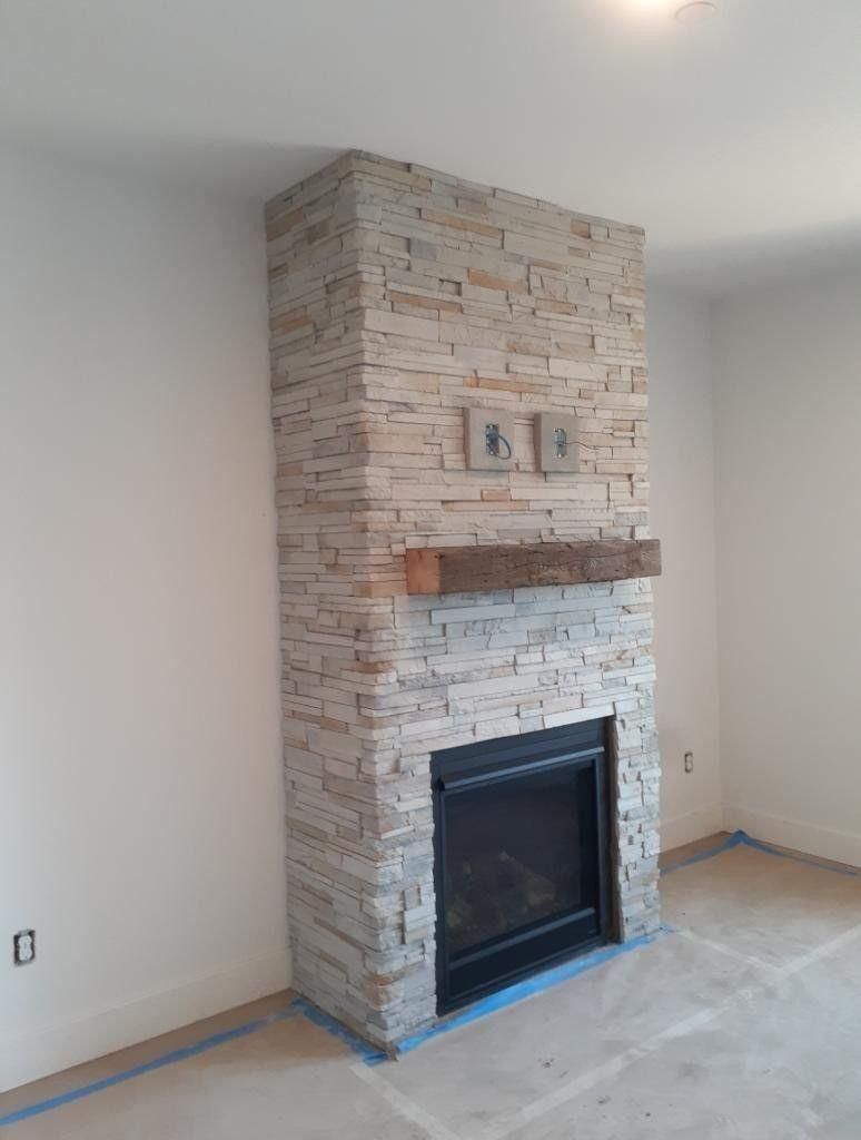 Living room with a stone fireplace surround and mantel against white walls, floor partly covered for painting