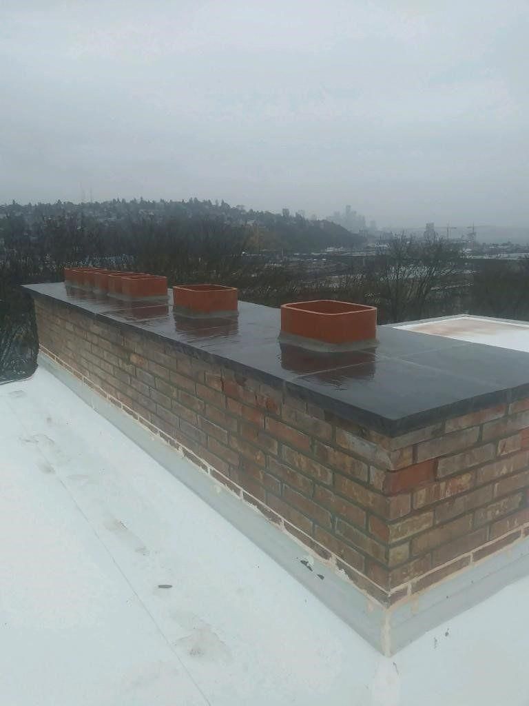 Snow-covered rooftop with three red chimney vents under a gray, overcast sky.