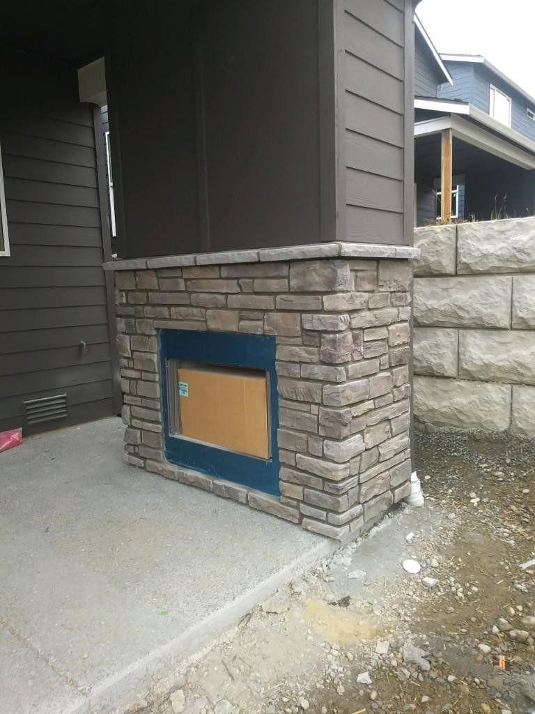 Exterior house wall with a small blue-trimmed access panel in stone siding