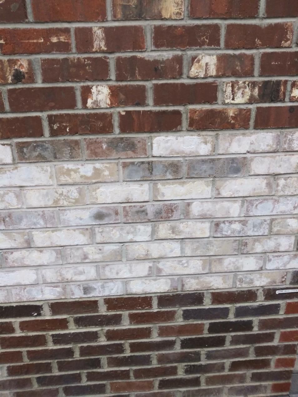 Brick wall with rows of red and white weathered bricks.