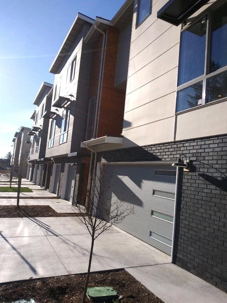 Modern townhouse exteriors with garages and a sidewalk in bright sunlight