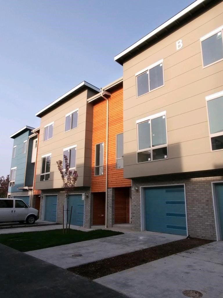 Modern apartment building exterior with beige and orange facades and a small courtyard walkway